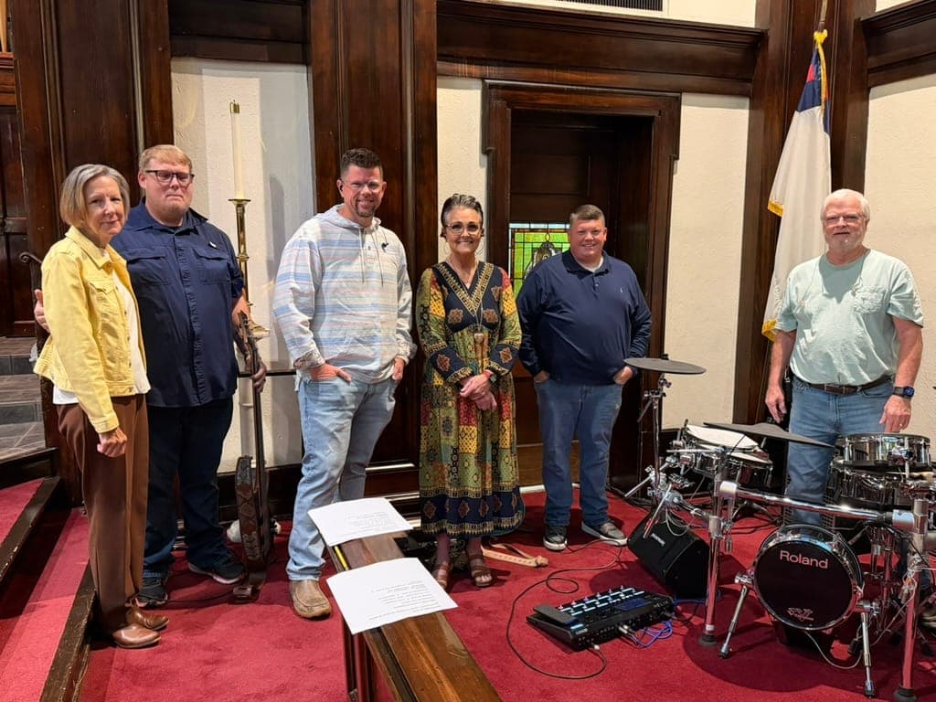 The Celebration Praise Band standing together in the sanctuary beside the drum kit